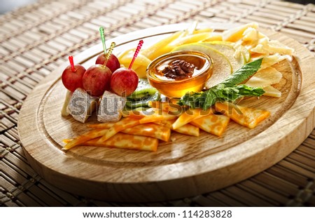 Not-ordinary snack plate with marble cheese,sliced apple,honey and grapes.