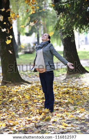 Yang and cute pregnant woman walks alone on Autumn background