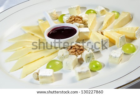 Plate of multiple kinds of cheeses topped with barbeque sauce.