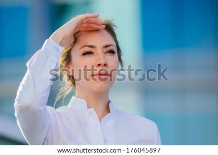Yang and beautiful modern business woman poses outdoor in urban background.