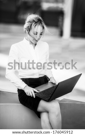 Yang and beautiful modern business woman poses outdoor with laptop.