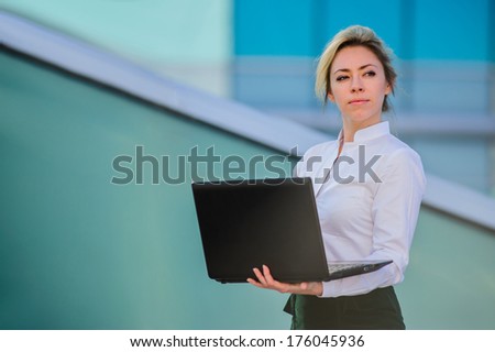 Yang and beautiful modern business woman poses outdoor with laptop.