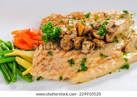 Plate of roasted chicken fillet with steamed vegetables and  mushrooms.