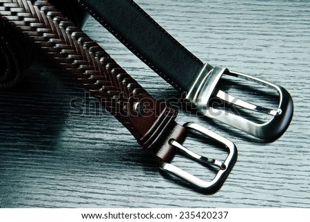 Two men\'s belts on grey table..