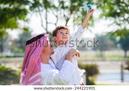 Arabic father and little kid play outdoors.