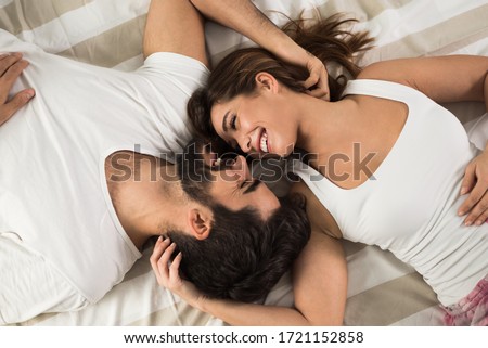 High angle view of smiling couple relaxing and lying down in bed .They are looking at each other