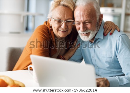 Embraced senior couple using laptop at home