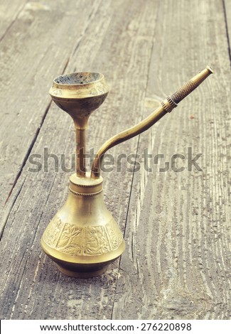 Small hookah copper on a wooden table. Vintage style toned photo.