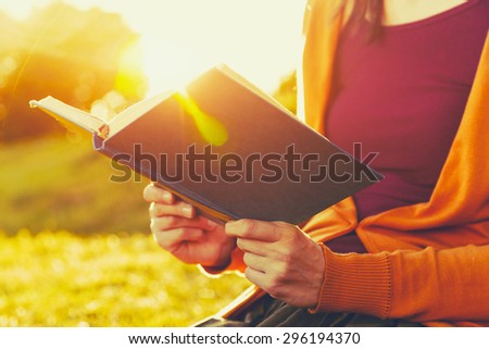 hands holding book and reading in summer sunset light