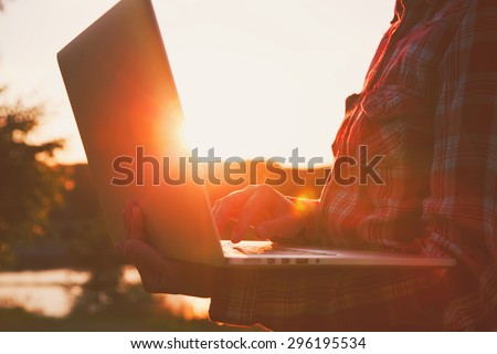 Hands using laptop and typing in the evening or morning on sunrise or sunset background