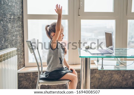 School girl  is studying online. Home schooling. Distance education. The girl raises her hand to answer the teacher's question. Photo stock © 