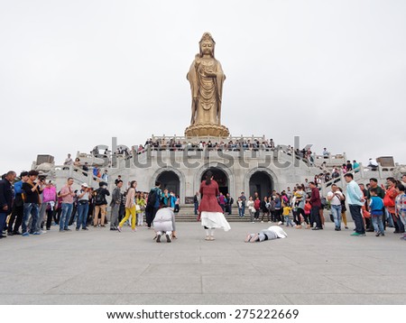 Putuoshan, CHINA - May 1, 2015: Three young ladies pray south sea Guanyin and crowded people watching.