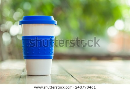 blue rubber coffee mug on blur green garden background