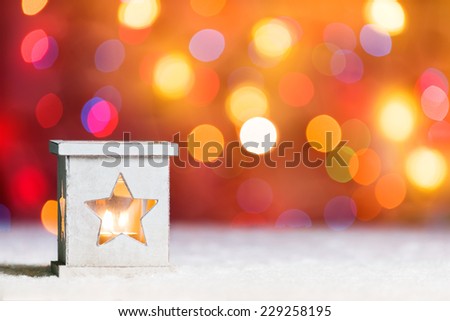 Burning candle, in snow, with defocussed fairy lights, boke in the background, Festive Christmas background with copyspace