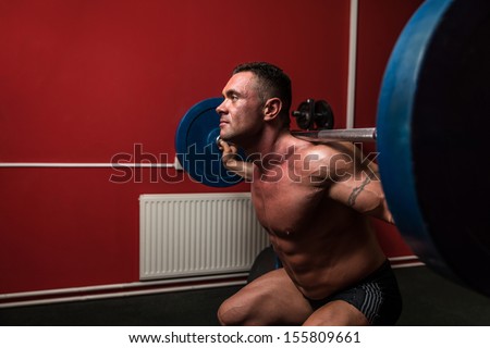 Body Builder doing squats with barbells