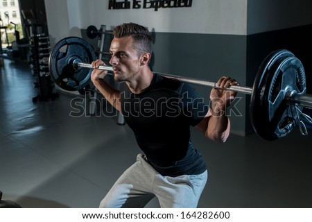 Man Doing Squats. Young Athlete Doing Barbell Squats