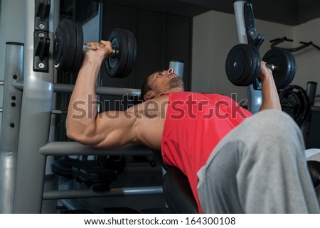 Dumbbell Training. Attractive Fit Men Lying On A Weight Bench Working Out With Dumbbell