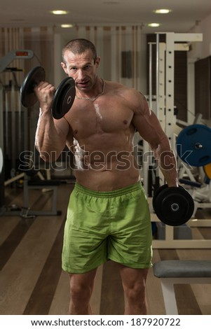 Body Builder Working Out Biceps In A Health Club