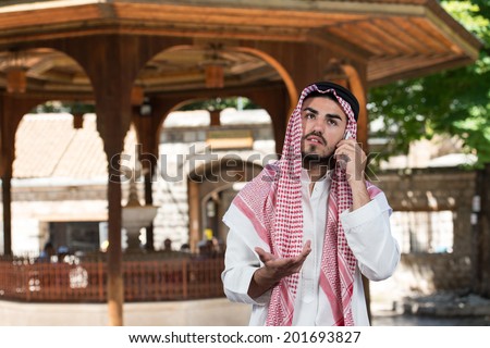Arab Saudi Emirates Man Using A Smart Phone - Young Businessman Wearing A Traditional Cap Dishdasha