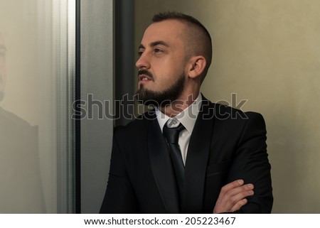 Young Business Man With Arms Folded Looking Out Window