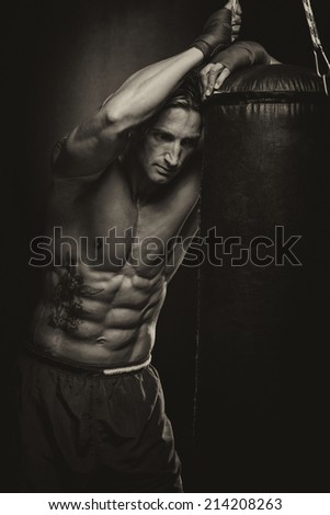 Attractive Man With Boxing Bag - A Man With A Tattoo In Red Boxing Gloves - Boxing On Black Background - The Concept Of A Healthy Lifestyle - The Idea For The Film About Boxing
