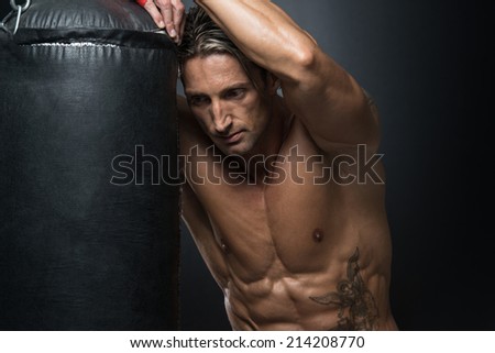 MMA Fighter Practicing With Boxing Bag - A Man With A Tattoo In Red Boxing Gloves - Boxing On Black Background - The Concept Of A Healthy Lifestyle - The Idea For The Film About Boxing