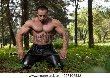 Portrait Of A Man With Ancient Sword - Standing In Forest Wearing Leather Pants
