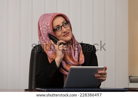 Muslim Business Woman Working At Her Computer While Talking On The Phone