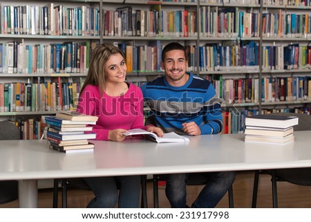 Portrait Of Clever Students With Open Book Reading It In College Library - Shallow Depth Of Field