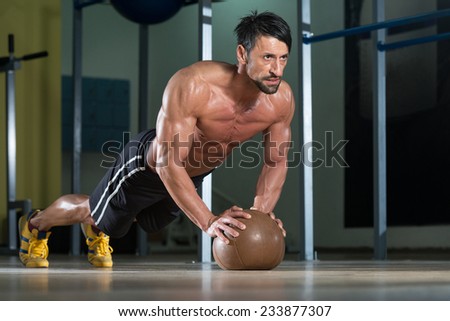 Attractive Male Athlete Performing Push-Ups On Medicine Ball