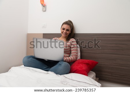 Young Woman Lying On Bed And Having Fun With Laptop In Bedroom