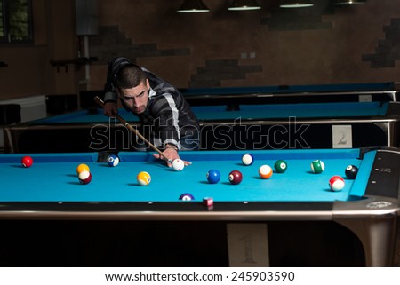 Young Man Lining To Hit Ball On Pool Table