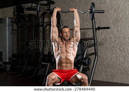 Muscular Mature Man Doing Heavy Weight Exercise For Triceps In Modern Fitness Center