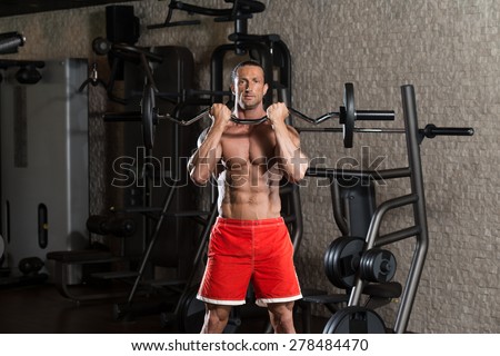 Muscular Mature Man Doing Heavy Weight Exercise For Biceps In Modern Fitness Center