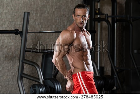 Mature Man Standing In Modern Fitness Center And Flexing Muscles