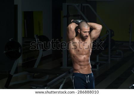 Muscular Young Man Doing Heavy Weight Exercise For Triceps In Gym