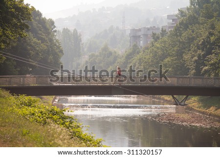 Young Man Running On Bridge In Wooded Forest Area - Training And Exercising For Trail Run Marathon Endurance - Fitness Healthy Lifestyle Concept