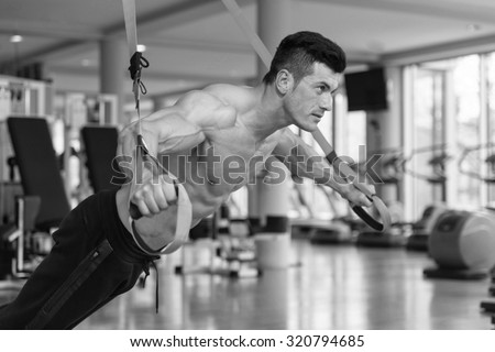 Attractive Man Does Crossfit Push Ups With Trx Fitness Straps In The Gym\'s Studio