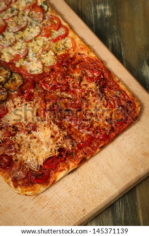 Square shaped homemade pizza four tastes on wooden board