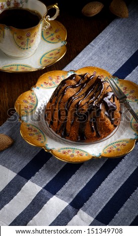 Mini Pound Cake - Hazelnut cake with chocolate drizzle with old pictures coffee cup, side plate and almonds
