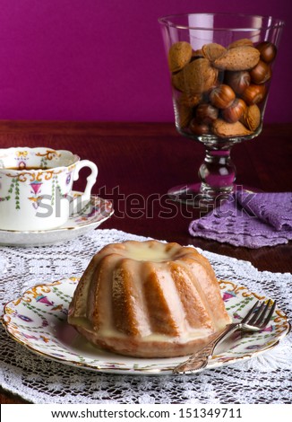 Mini Pound Cake - Almond lemon drizzle cake on old pictures coffee cup, side plate on lace and glass cup full of almonds and hazelnuts, purple background