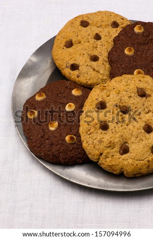 White and dark chocolate chip cookies on tin plate, white canvas