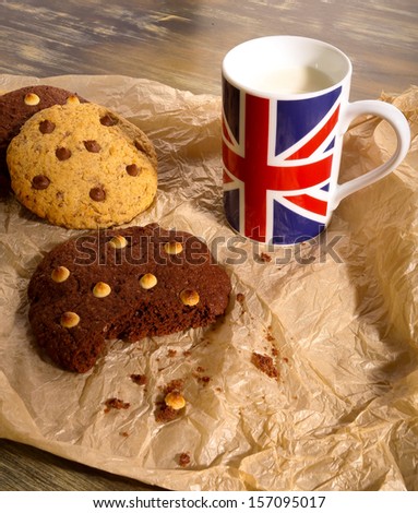 White and dark chocolate chip cookies with milk in English flag mug on crumpled light brown paper