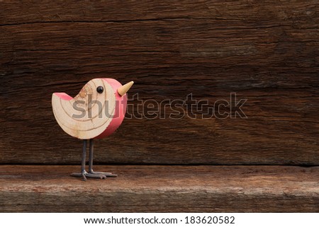 Wooden pink toy bird figure symbol on old rough background with copy space