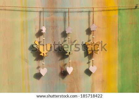 Hanging decor wooden birds, hearts and butterfly on strong over painted background