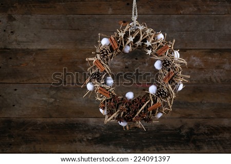 Decorated christmas wreath with cotton buds, pine cones, anise and cinnamon sticks on brown twigs,  old wooden rustic background, copy space