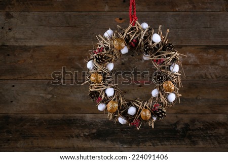Decorated christmas wreath with walnuts, cotton buds, brown twigs and pine cones on old wooden rustic background, copy space