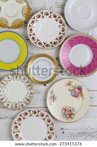 Set of plates with antique figure border pattern assorted vintage china on white painted rough wood background