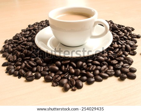 cup of coffee and many coffee beans on the wooden table