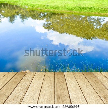 Empty perspective wooden plank floor over the reflection of trees in water, product display template